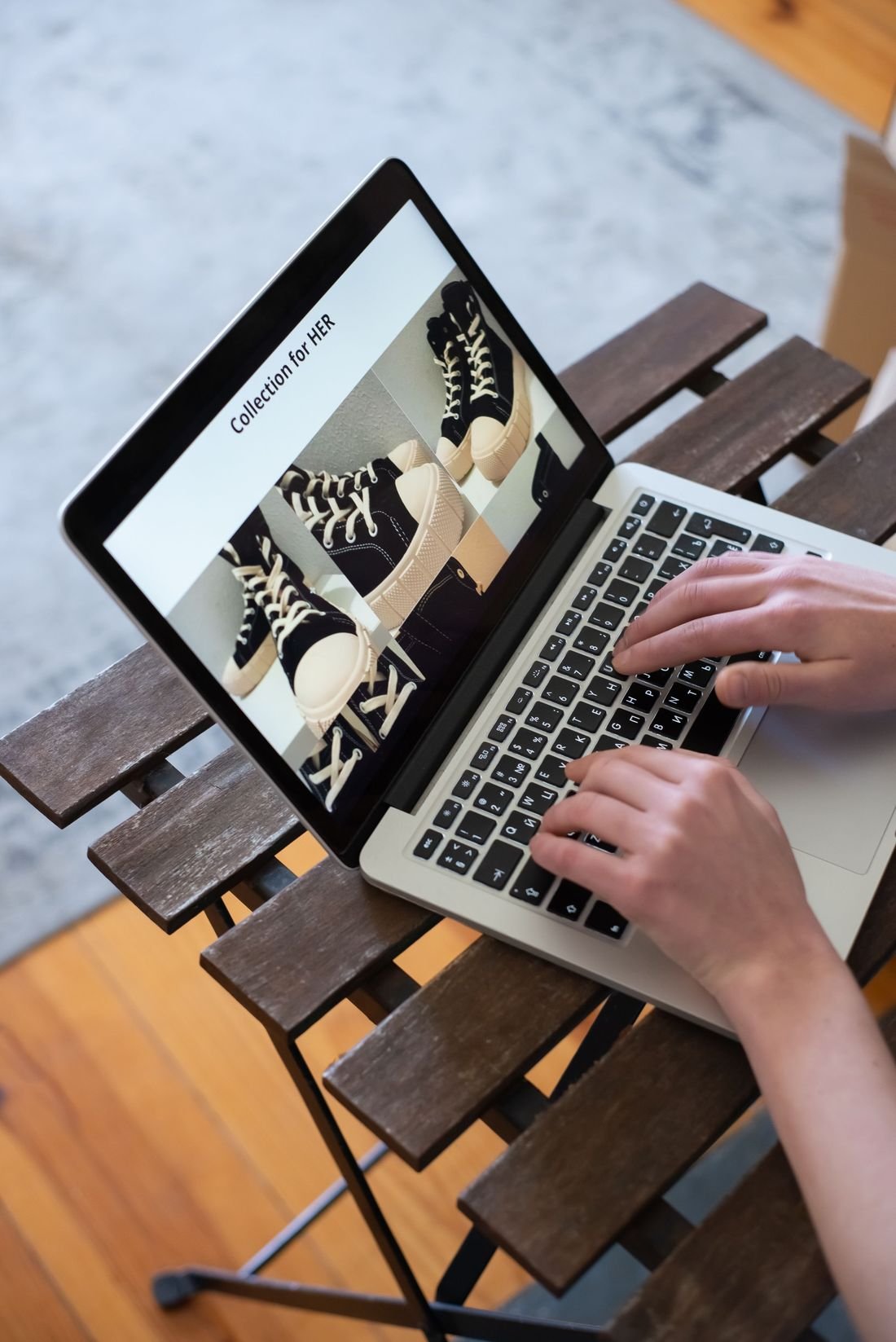 Hands typing on a laptop that shows an online sneaker collection page